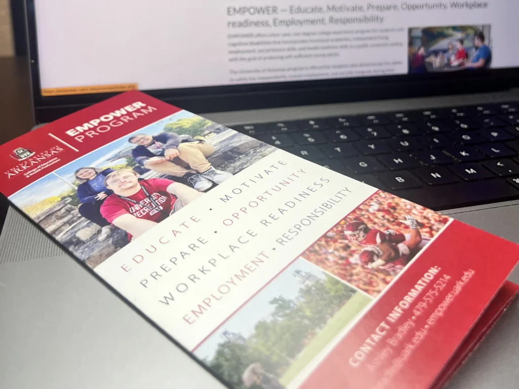 University of Arkansas EMPOWER Program brochure displayed on laptop keyboard.